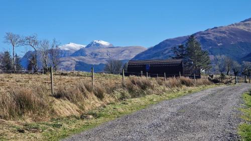 a train on a dirt road with mountains in the background at Dalrigh Pod in Onich
