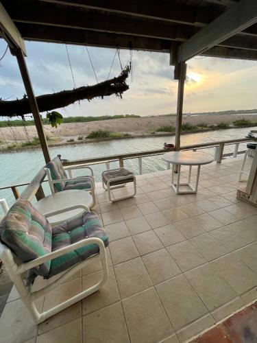 a porch with chairs and a table and water at Heron's Sea Cottage with view of Space X and just minutes from South Padre Island in Port Isabel