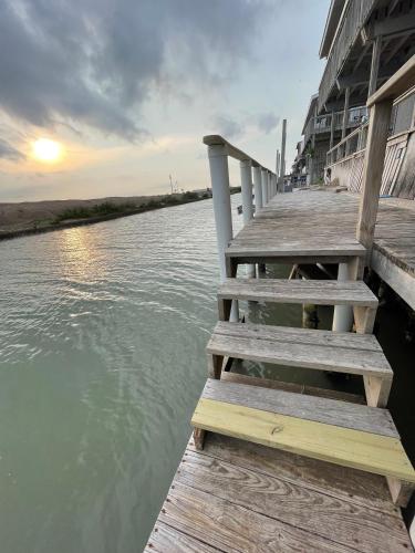 a wooden dock on a body of water at Heron's Sea Cottage with view of Space X and just minutes from South Padre Island in Port Isabel