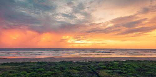 a sunset on a beach with the ocean at Heron's Sea Cottage with view of Space X and just minutes from South Padre Island in Port Isabel