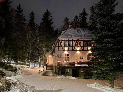 une grande maison dans la neige la nuit dans l'établissement Mon Plaisir, à Karpacz