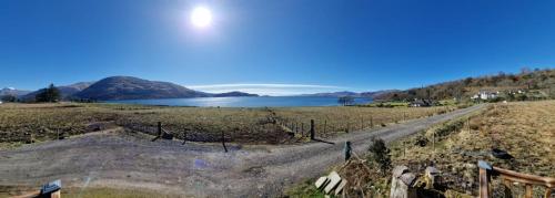a dirt road in a field next to a lake at Dalrigh Pod in Onich