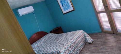 een slaapkamer met een bed en een blauwe muur bij Estancia La Paulina in Eldorado