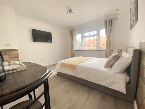 a bedroom with a bed and a table and a television at Gatwick Deluxe En-suite Rooms in Horley