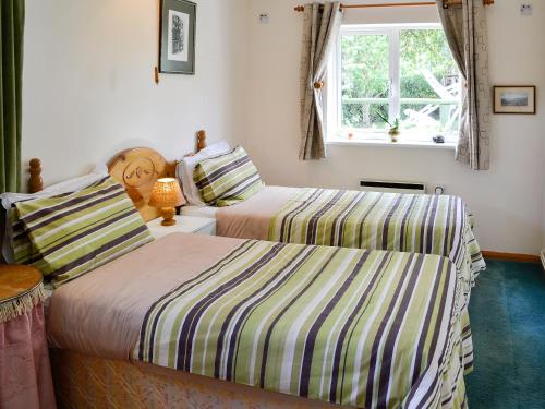 a bedroom with two beds and a window at Russets East Wing in Isle Brewers