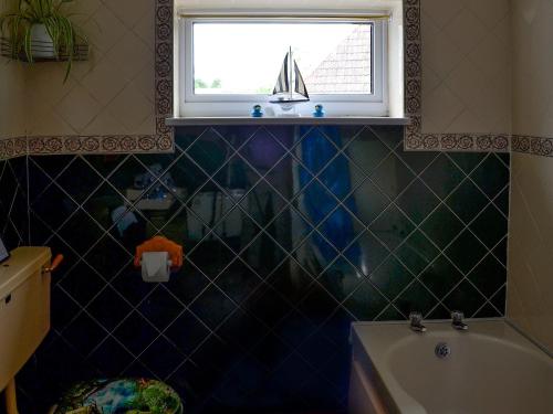 een badkamer met een bad en een raam met een zeilboot erin bij Russets East Wing in Isle Brewers