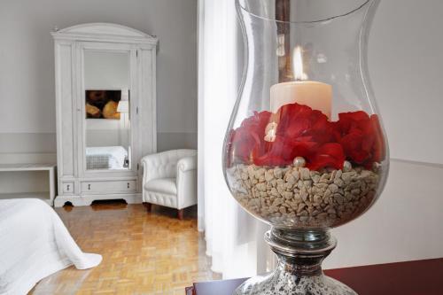 a candle in a glass vase with rocks and flowers at Hotel Villa Quiete in Montecassiano