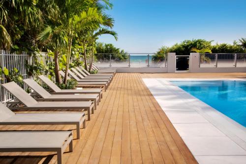 a row of white lounge chairs next to a swimming pool at MB Hotel, Trademark Collection by Wyndham in Miami Beach