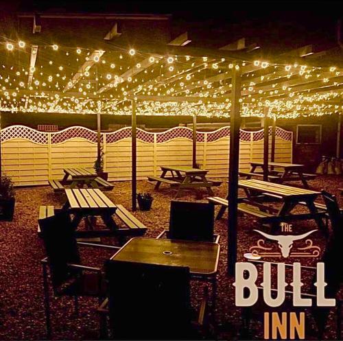 a group of picnic tables under a tent with lights at The Coach House at The Bull Inn in Milton Keynes