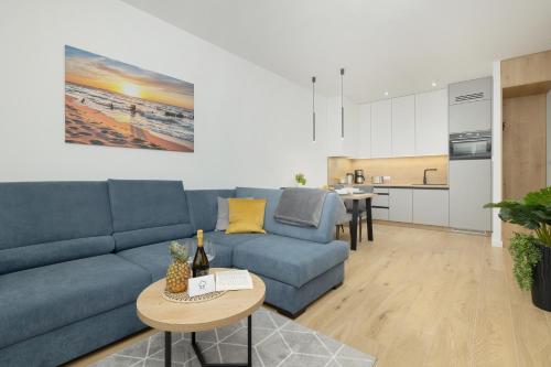 a living room with a blue couch and a kitchen at Apartament AQUA BLUE Bridge Apartments & Spa Dziwnów EPapartamenty in Dziwnów