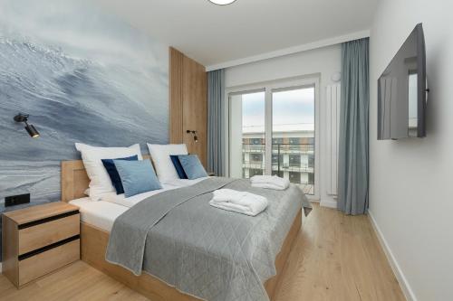 sypialnia z łóżkiem i obrazem na ścianie w obiekcie Apartament AQUA BLUE Bridge Apartments & Spa z basenem Dziwnów EPapartamenty w Dziwnowie