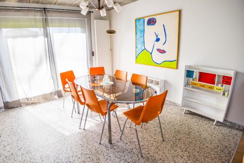 a dining room with a glass table and orange chairs at Paulette à bicyclette in Méry