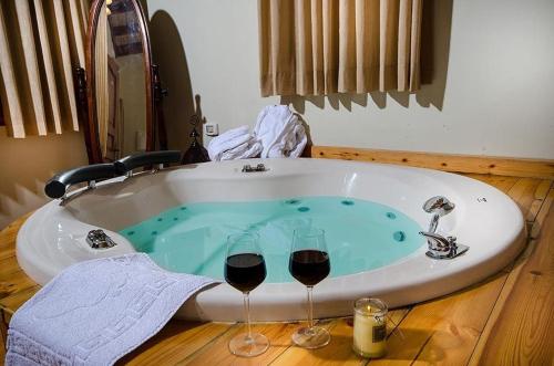 une baignoire avec deux verres de vin rouge dans l'établissement אתנחתא בירדן, à Mishmār Hāyardin