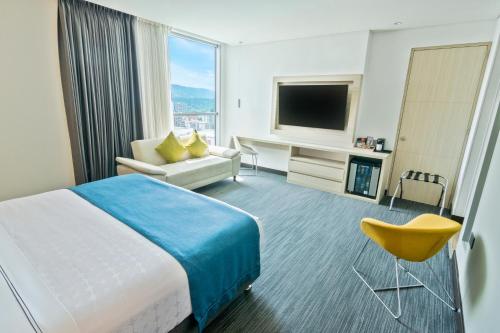 Cette chambre comprend un lit, un canapé et une télévision. dans l'établissement Sonesta Hotel Bucaramanga, à Bucaramanga