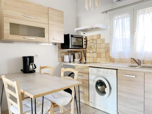 a kitchen with a table and a washing machine at Maisonnette proche Mer Terrasse Parking Climatisée in Villeneuve-Loubet