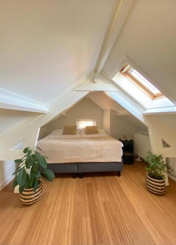 a attic bedroom with a bed and two potted plants at The Lighthouse Cabin in Noordwijk