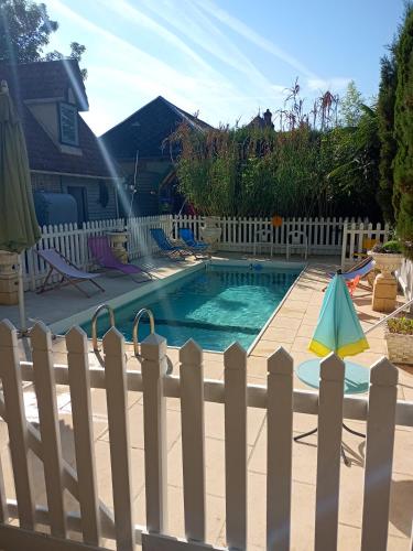 une piscine dans le jardin avec une clôture blanche et une piscine dans l'établissement Bergerie Bracquetuit, à Bracquetuit