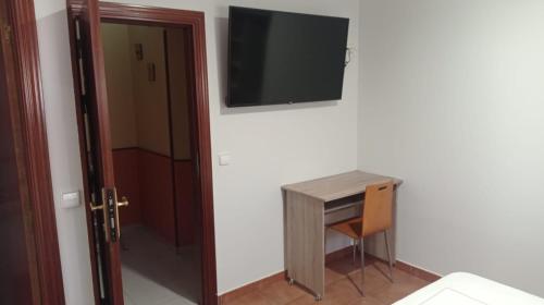 a room with a desk and a television on a wall at Alojamiento Numancia Pensión in Burgos