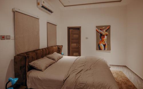 a bedroom with a bed with a painting on the wall at Big chill stays in Accra