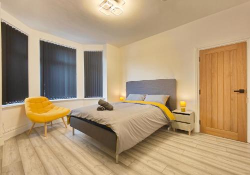 a bedroom with a bed and a chair and windows at Lindsay House - South Manchester Stylish Townhouse With Free Parking in Manchester