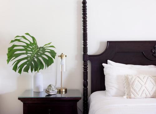 a bedroom with a bed with a plant on a night stand at Lumeria Maui, Educational Retreat Center in Makawao