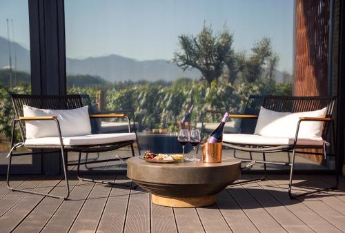 a patio with two chairs and a table with wine glasses at Vibo Wine Lodge At Viu Manent in Santa Cruz