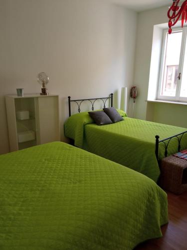 2 camas en una habitación con sábanas verdes en Forte Sangallo Home - PARKING POINT FOR BIKE, en Civita Castellana