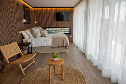 een slaapkamer met een bed, een tafel en een stoel bij Vibo Wine Lodge At Viu Manent in Santa Cruz