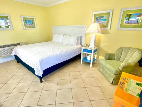a bedroom with a bed and a chair and a lamp at Island Inn of Atlantic Beach in Atlantic Beach