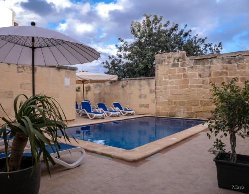 a swimming pool with chairs and an umbrella at Sunny Villa in Nadur