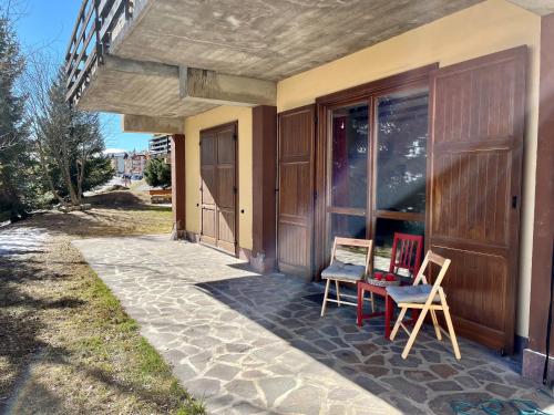 a porch of a house with two chairs and a table at La Casa Bianca - ski, hike & bike in Passo del Tonale