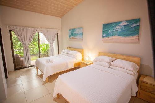 a bedroom with two beds and a window at Hotel Por Que No? in Uvita