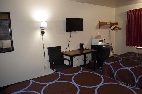 a hotel room with a bed and a desk and a television at AmeriVu Inn and Suites Shawano WI in Shawano
