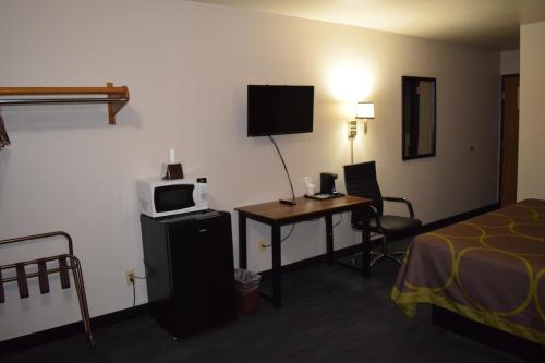 a hotel room with a bed and a desk with a microwave at AmeriVu Inn and Suites Shawano WI in Shawano