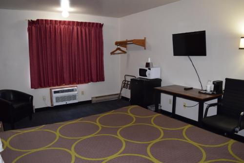 a living room with a red window and a desk with a television at AmeriVu Inn and Suites Shawano WI in Shawano