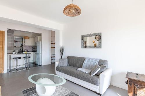 ein Wohnzimmer mit einem Sofa und einem Tisch in der Unterkunft Appt lumineux et spacieux au cœur de Cannes in Cannes