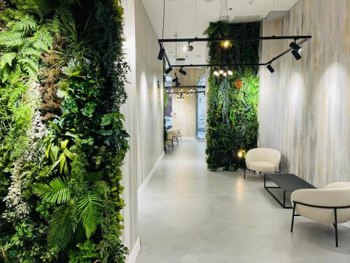 a corridor with a green wall with chairs and plants at Hotel Central Basilica in Budapest