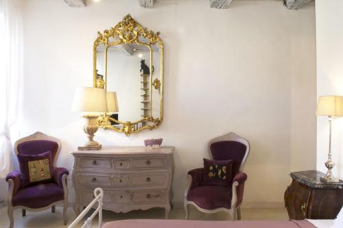 a room with a dresser and two chairs and a mirror at Le Stanze del Cardinale in Pavia