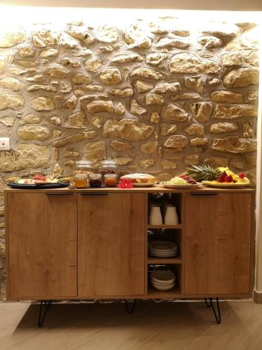 a wooden cabinet with food on it in front of a stone wall at Panorama Suite in Piazza Armerina