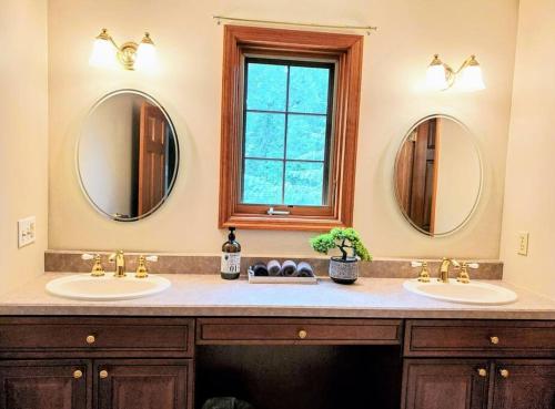 a bathroom with two sinks and two mirrors at Artemis Lakehouse - Hot Tub, Lakefront & Racetrack in Saratoga Springs