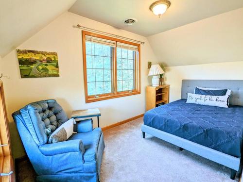 a bedroom with a blue bed and a couch at Artemis Lakehouse - Hot Tub, Lakefront & Racetrack in Saratoga Springs