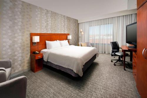 a hotel room with a bed and a desk and a television at Courtyard by Marriott Wichita Falls in Wichita Falls