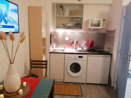 une cuisine avec un lave-linge et un micro-ondes dans l'établissement Studio bord de mer, à Courseulles-sur-Mer