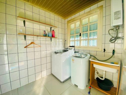 ein kleines Badezimmer mit Waschmaschine und Trockner in der Unterkunft Casa ampla e aconchegante em Gramado in Gramado