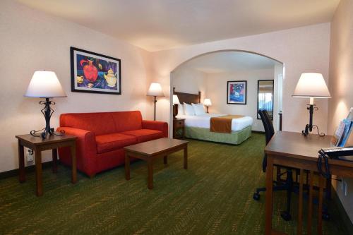 a hotel room with a red couch and a bed at Lamplighter Inn & Suites at SDSU in San Diego