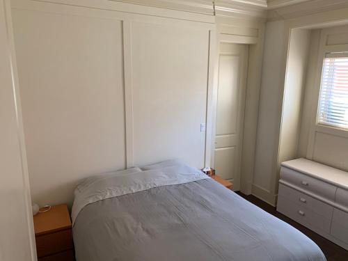 a white bedroom with a bed and a window at Private cozy suite near Dyke and Fisherman's Wharf in Richmond
