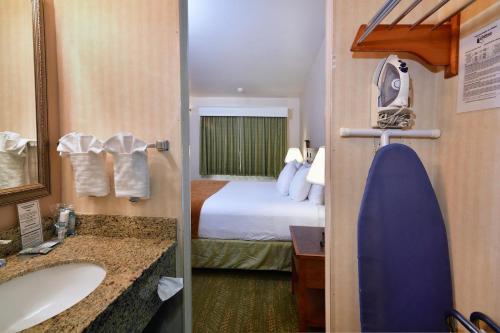 a hotel room with a bed and a bathroom at Lamplighter Inn & Suites at SDSU in San Diego