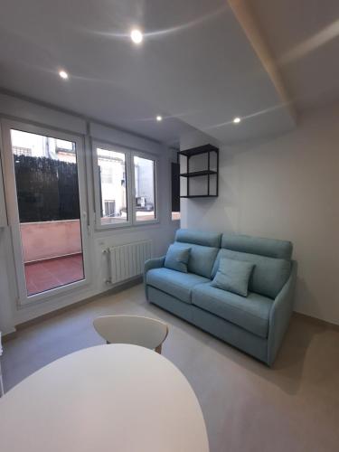 een woonkamer met een blauwe bank en ramen bij Apartamentos Sudestada in Logroño