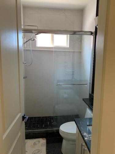 a bathroom with a toilet and a glass shower at Private cozy suite near Dyke and Fisherman's Wharf in Richmond