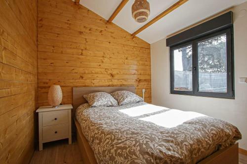 a bedroom with a bed with a wooden wall at Chalet 2 chambres parking, à 5 min à pieds d'Etretat in Bordeaux-Saint-Clair